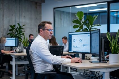 Consultant IT professionnel analysant des tableaux de bord numériques sur deux écrans dans un bureau moderne Septeo IT Solutions