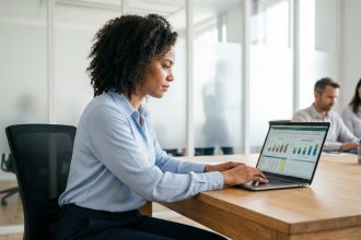 Femme analysant des données de rémunération sur un ordinateur portable avec des graphiques salariaux dans un bureau moderne